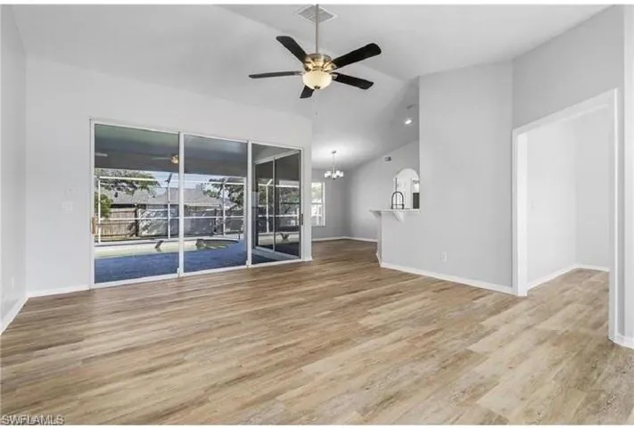 Unfurnished living room with lofted ceiling, ceiling fan, a chandelier, and wood finished floors