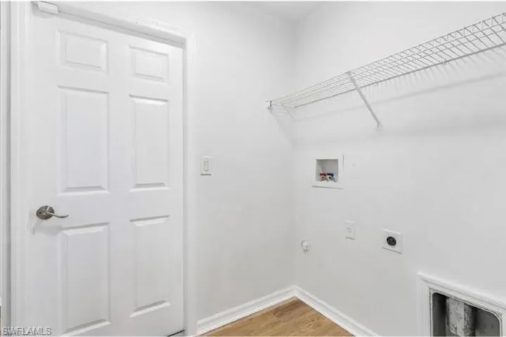 Laundry area with electric dryer hookup, hookup for a washing machine, and wood finished floors