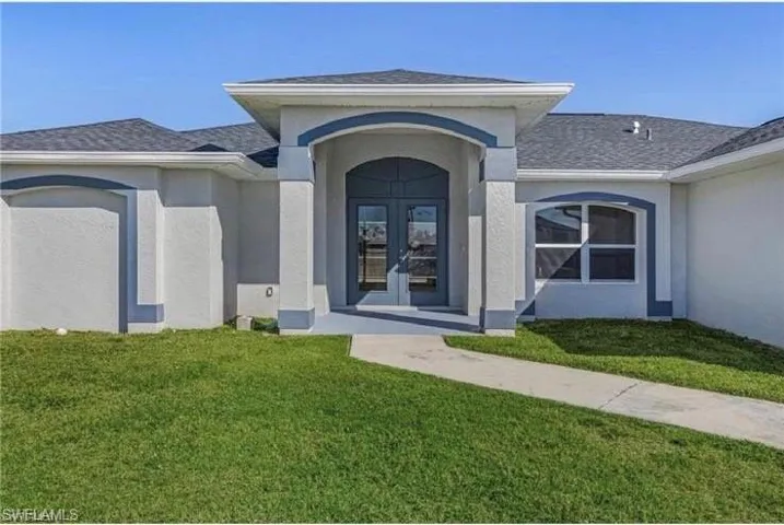 Property entrance featuring a lawn, stucco siding, french doors, and roof with shingles