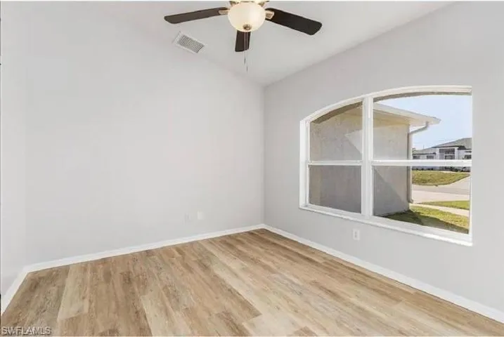 Unfurnished room featuring wood finished floors, a ceiling fan, and vaulted ceiling
