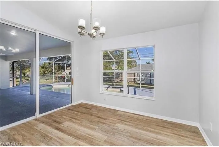 Spare room with a chandelier and wood finished floors