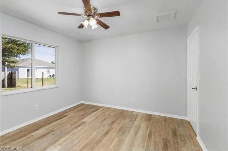 Empty room with light wood-style flooring, attic access, and a ceiling fan