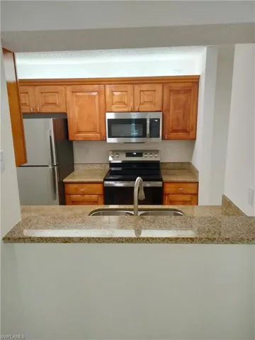 Kitchen featuring sink, stainless steel appliances, and light stone countertops