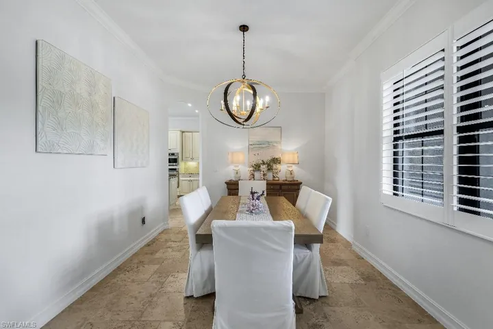 Recessed dining area featuring crown molding, neutral wall tones, and tiled flooring