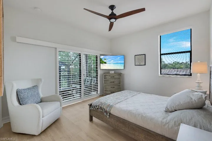 Bright interior room with wood-finish flooring, a contemporary ceiling fan, and a built-in wall-mounted television