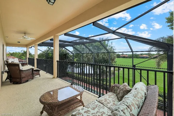 Screened upper-level patio with textured flooring, wrought iron railing, and a ceiling fan
