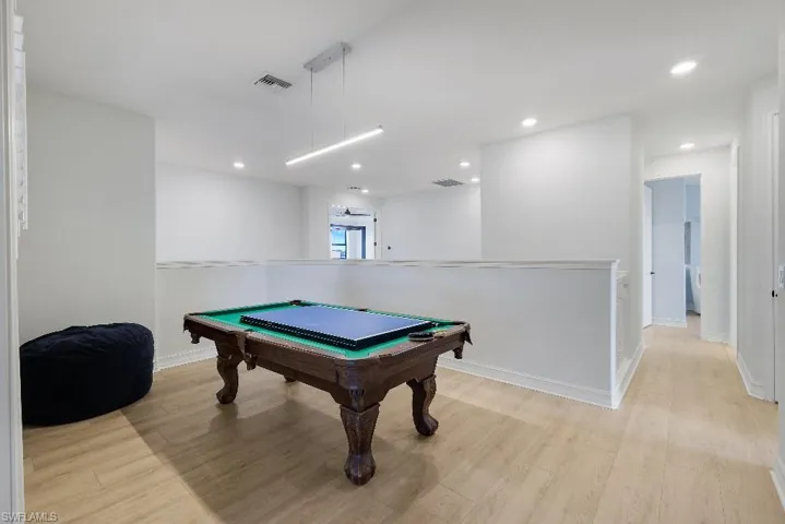 Bright upper-level space featuring light wood-finish flooring, recessed lighting, and a contemporary linear pendant light fixture