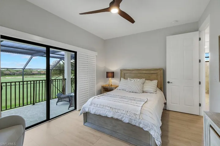 Room featuring sliding glass doors to a screened balcony, wood-finish flooring, a ceiling fan, and a paneled interior door