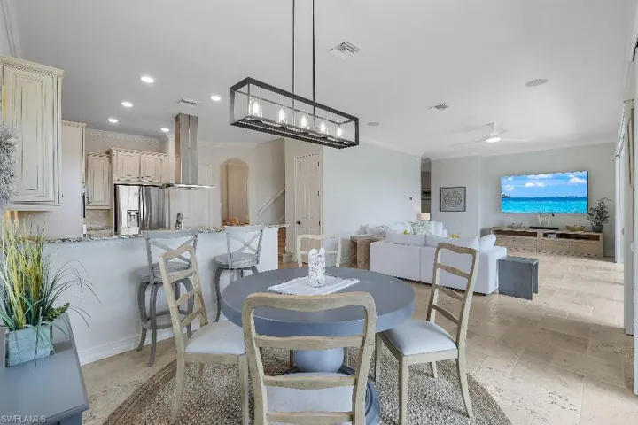 Open-concept living space featuring light-toned flooring, recessed lighting, and crown molding