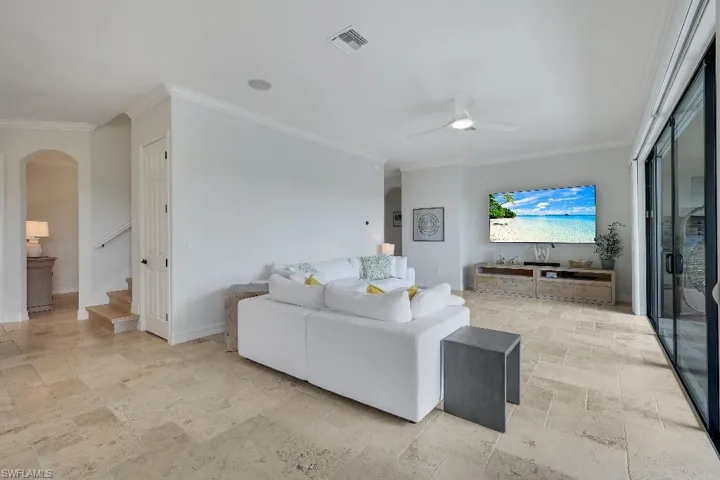 Spacious living area featuring neutral-toned tile flooring, recessed lighting, and crown molding