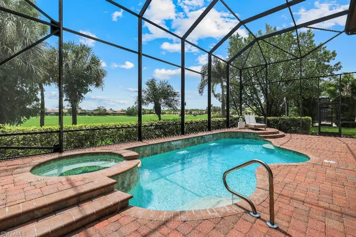 Screened outdoor living area featuring a freeform swimming pool with integrated spa