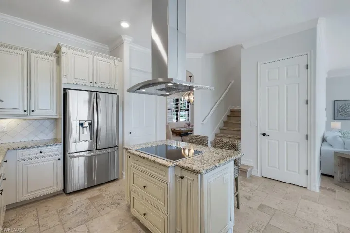 Contemporary kitchen featuring a center island with a cooktop, granite countertops, stainless steel appliances, and white cabinetry