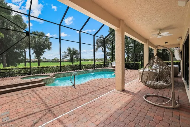 Screened lanai featuring a swimming pool and attached spa, surrounded by brick paver decking