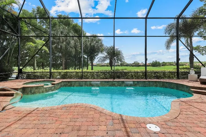 Screened outdoor living area featuring a freeform swimming pool with integrated spa and waterfall features