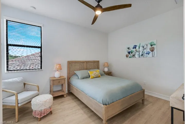 Light-filled room featuring wood-finish flooring, white walls, and a ceiling fan with integrated lighting