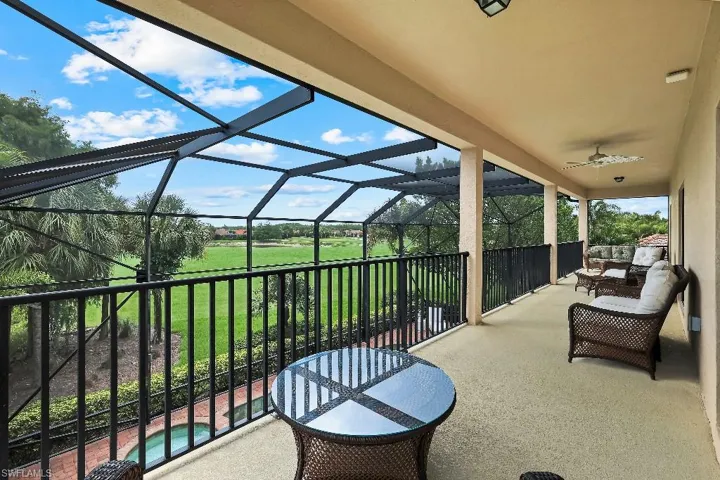 Expansive screened balcony featuring a textured concrete floor, column supports, and a ceiling fan