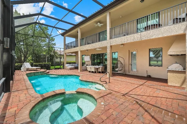 Screened outdoor living area featuring a freeform pool and integrated spa