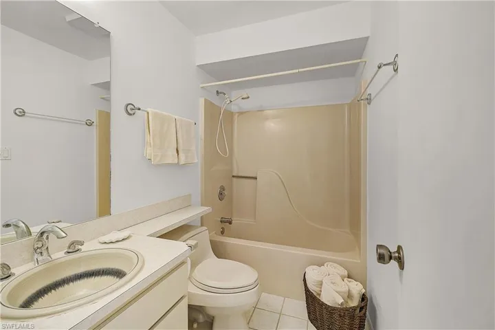Bathroom with vanity, bathing tub / shower combination, and light tile patterned floors