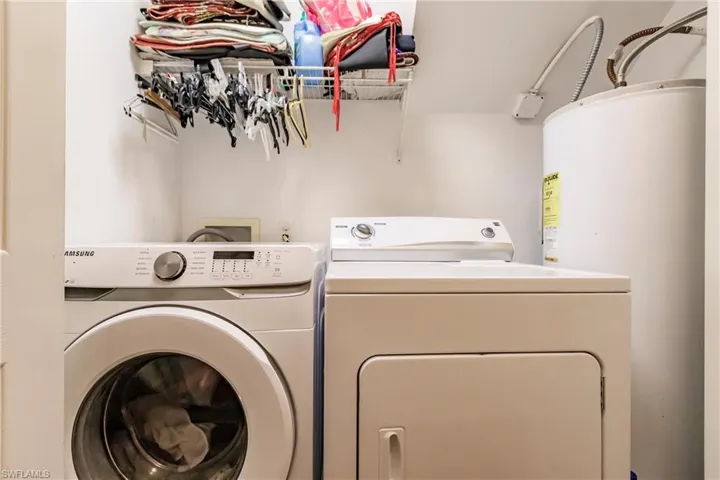 Clothes washing area featuring separate washer and dryer and water heater