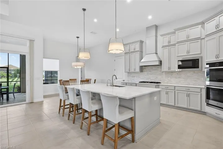 Kitchen with a kitchen bar, a center island with sink, recessed lighting, tasteful backsplash, and decorative light fixtures