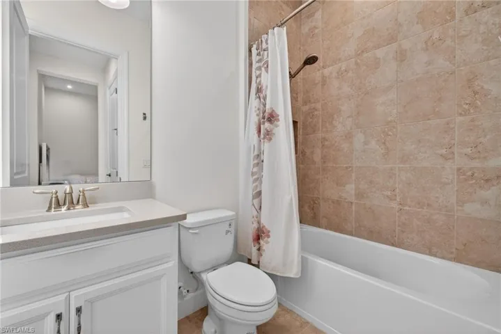 Bathroom with shower / bathtub combination with curtain, vanity, and light tile patterned floors