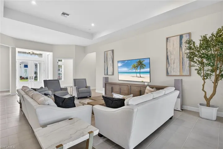 Living area with french doors, a raised ceiling, light tile patterned floors, and recessed lighting