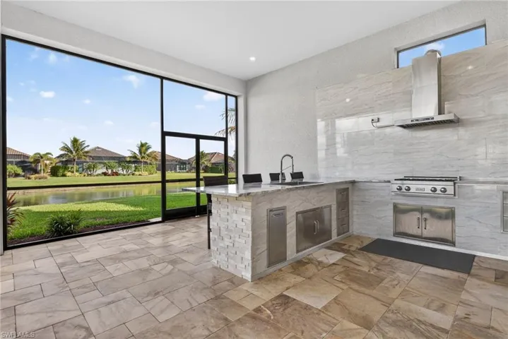 Kitchen with light stone counters, healthy amount of natural light, a water view, wall chimney range hood, and a textured wall