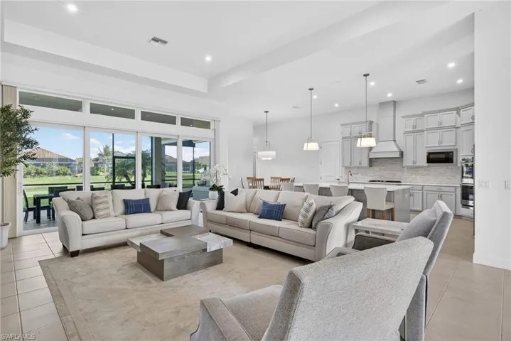 Living area with light tile patterned flooring, recessed lighting, and a tray ceiling