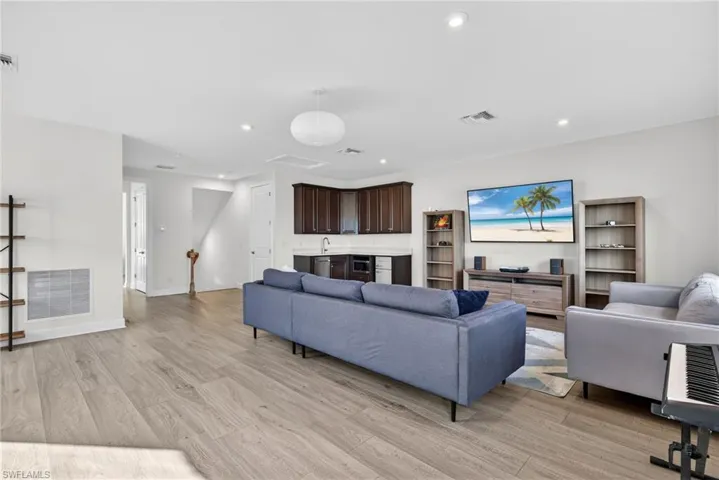Living room with light wood-style floors, recessed lighting, and beverage cooler