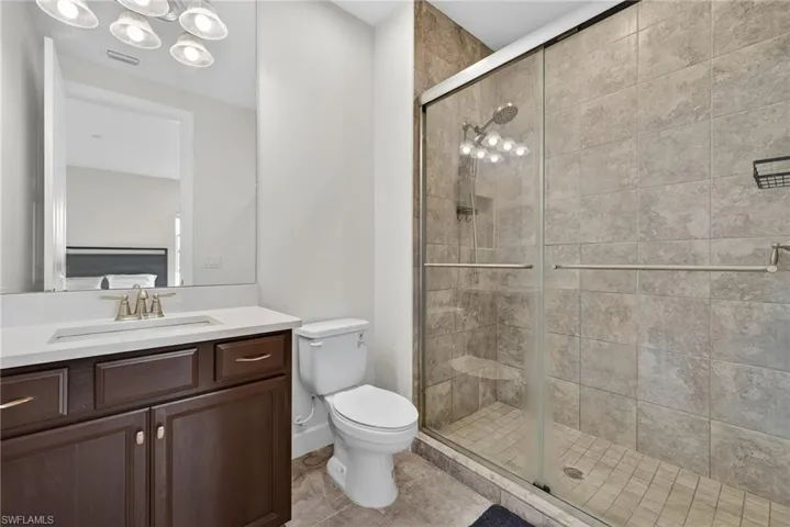 Full bathroom featuring vanity, a stall shower, light tile patterned floors, and a chandelier