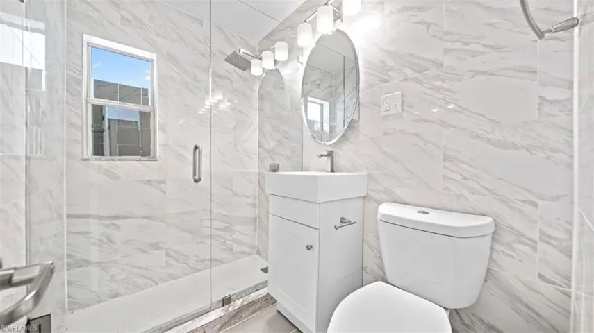 Full bathroom featuring tile walls, vanity, and a marble finish shower