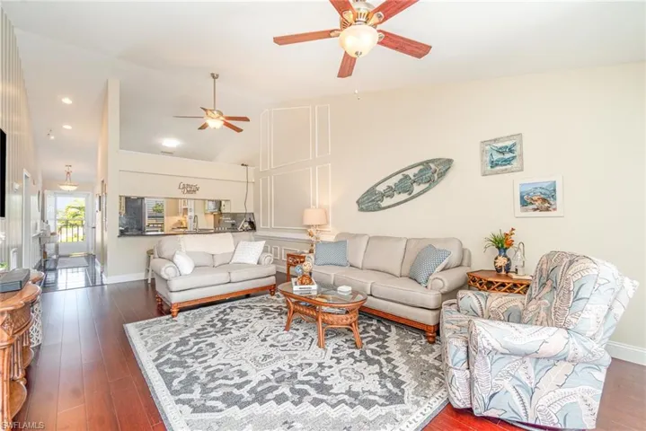 Living area with ceiling fan, vaulted ceiling, dark wood-style flooring, and recessed lighting