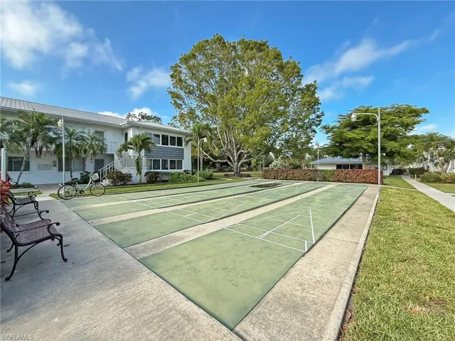 View of community with shuffleboard and a lawn