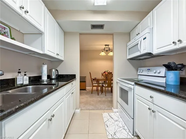 Kitchen with white cabinets, white appliances, open shelves, and light tile patterned floors
