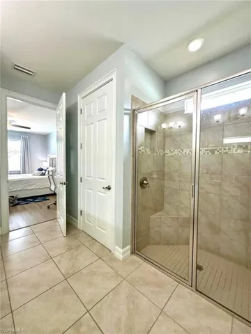Bathroom with connected bathroom, a stall shower, and tile patterned floors