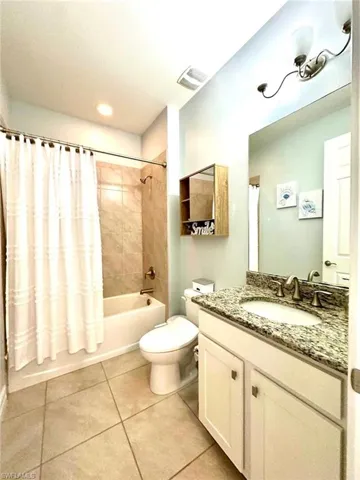 Bathroom with tile patterned floors, shower / bath combination with curtain, vanity, and recessed lighting