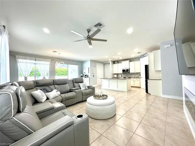 Living area with light tile patterned floors, a ceiling fan, and recessed lighting