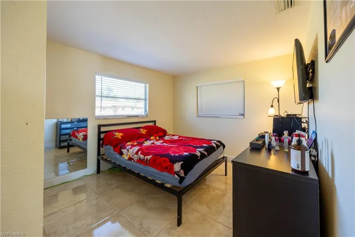 Spacious room featuring tile flooring, two windows with horizontal blinds, and a neutral wall color