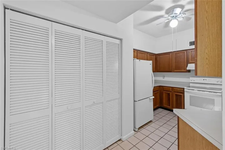 Kitchen featuring white appliances, light tile flooring, and ceiling fan
