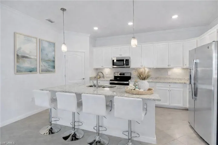Kitchen with stainless steel appliances, white cabinets, backsplash, and ornamental molding