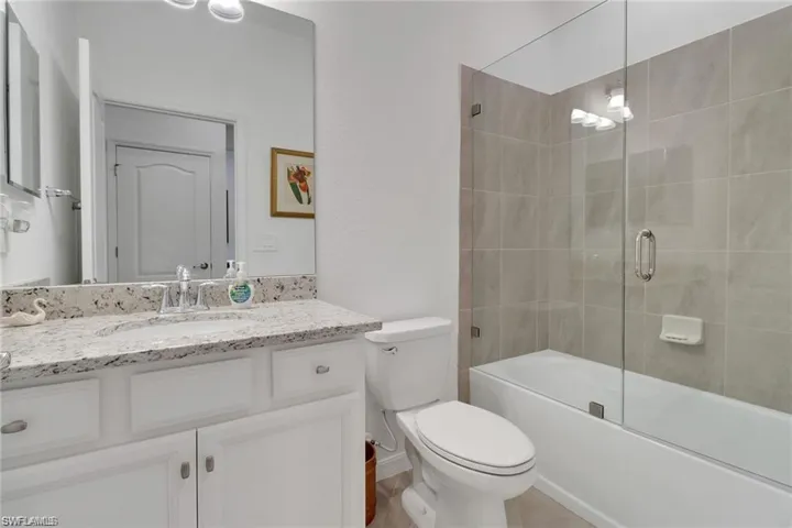 Bathroom with vanity and combined bath / shower with glass door
