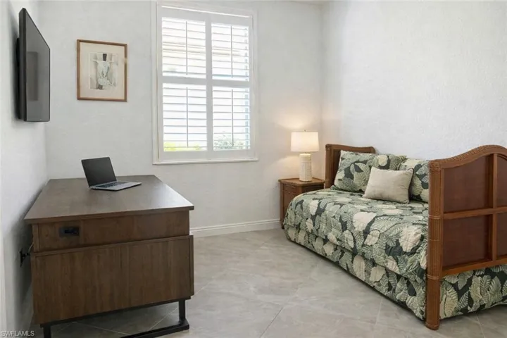 Bedroom featuring an office area and a textured wall