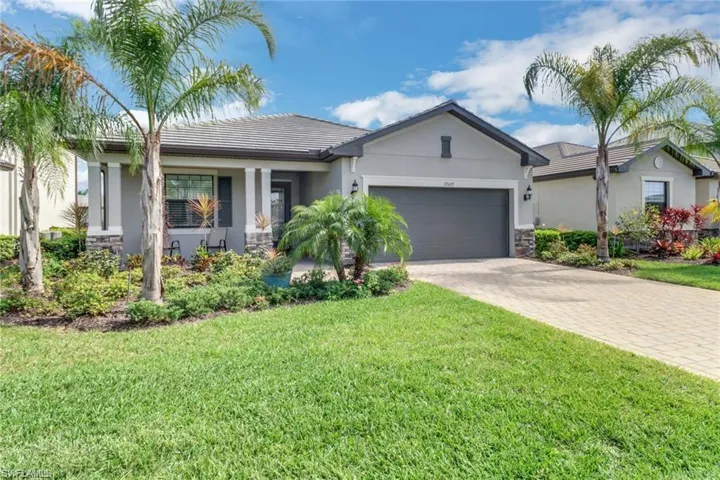 Ranch-style home with stone siding, a garage, stucco siding, decorative driveway, and a front yard