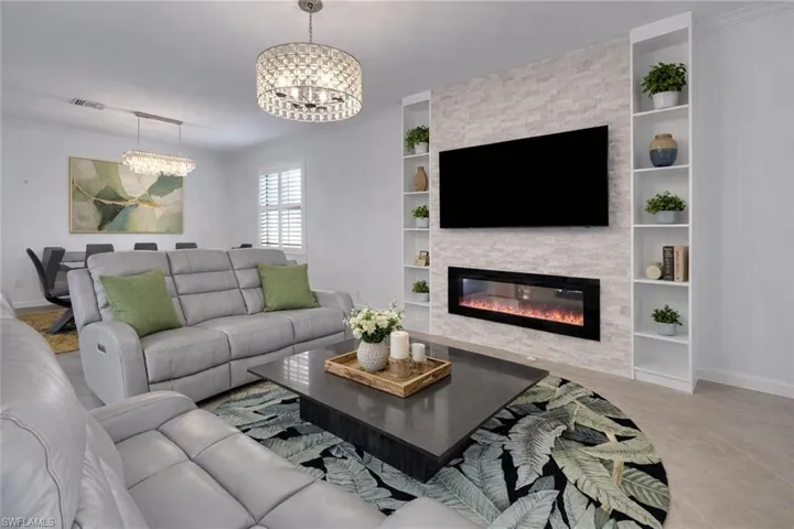 Living area featuring ornamental molding, hanging lights, a fireplace, and built in shelves