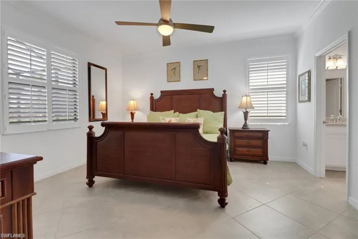 Bedroom featuring ornamental molding, connected bathroom, a ceiling fan, and light tile patterned floors