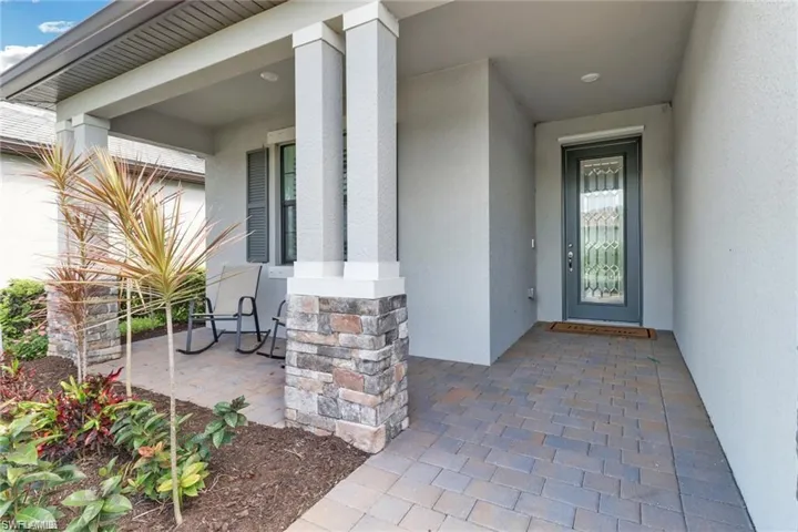 Entrance to property with covered porch and stucco siding