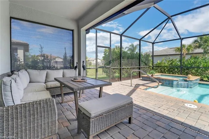 View of patio / terrace with a sunroom, a pool with connected hot tub, outdoor furniture, and glass enclosure