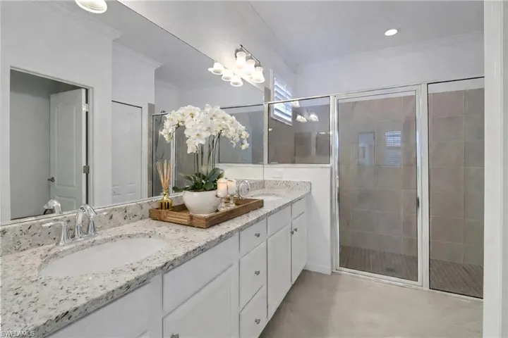 Full bathroom featuring double vanity, a stall shower, ornamental molding, and recessed lighting
