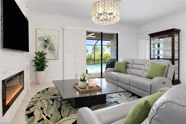 Living room with ceiling fan, suspended lighting, ornamental molding, and a fireplace