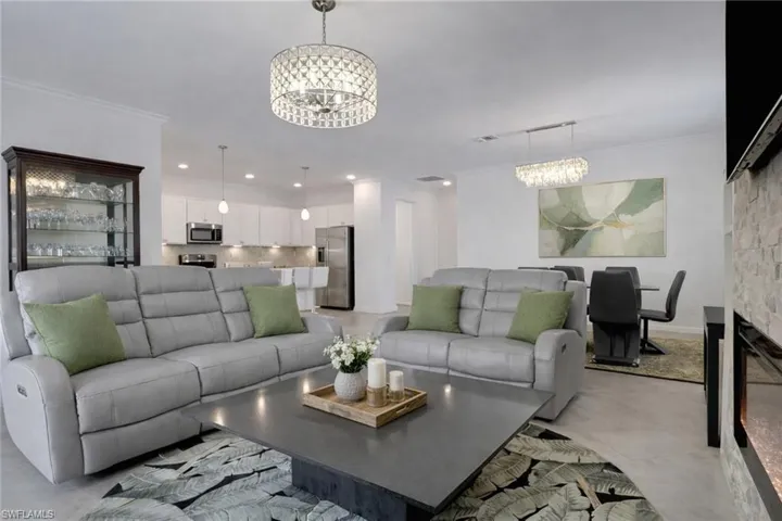 Living area featuring suspended lighting, ornamental molding, and concrete flooring